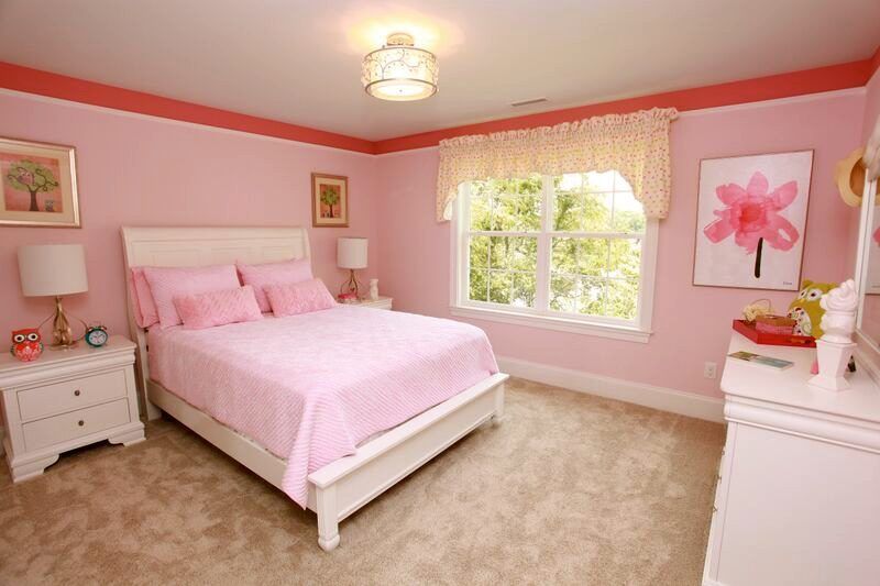 A bedroom with pink walls and a white bed.