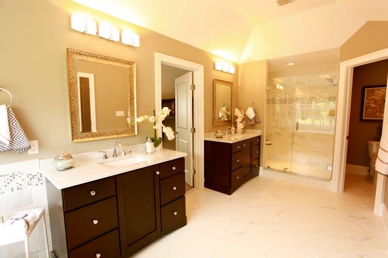 A bathroom with two sinks , two mirrors and a walk in shower.