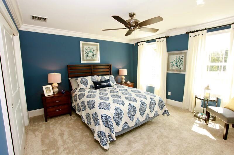 A bedroom with blue walls and a ceiling fan