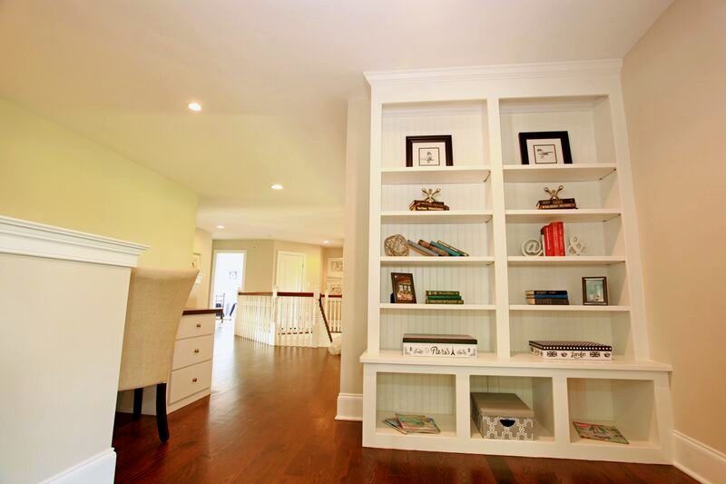 A living room with hardwood floors and white shelves