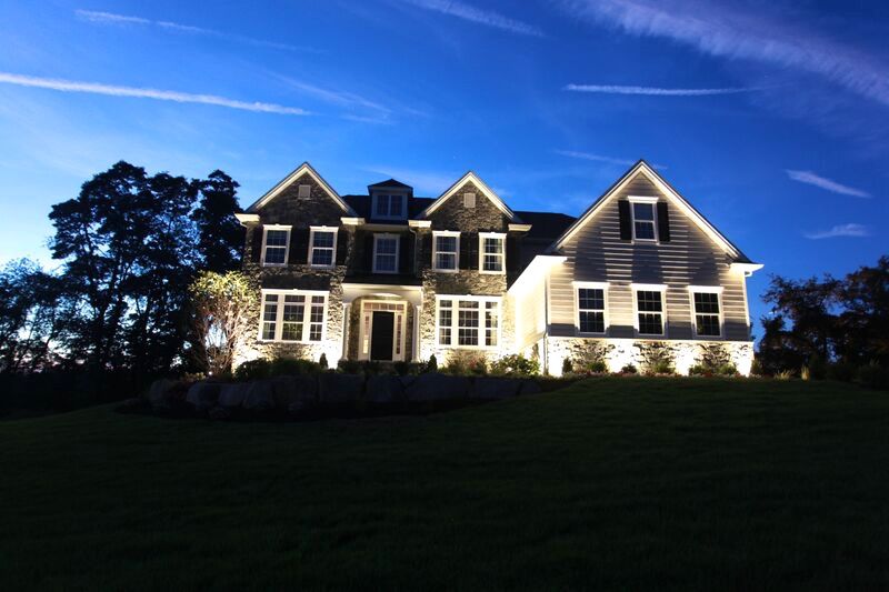 A large house is lit up at night with a blue sky in the background