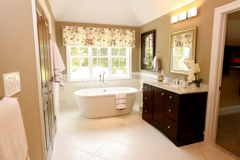 A bathroom with a tub , sink , mirror and window.
