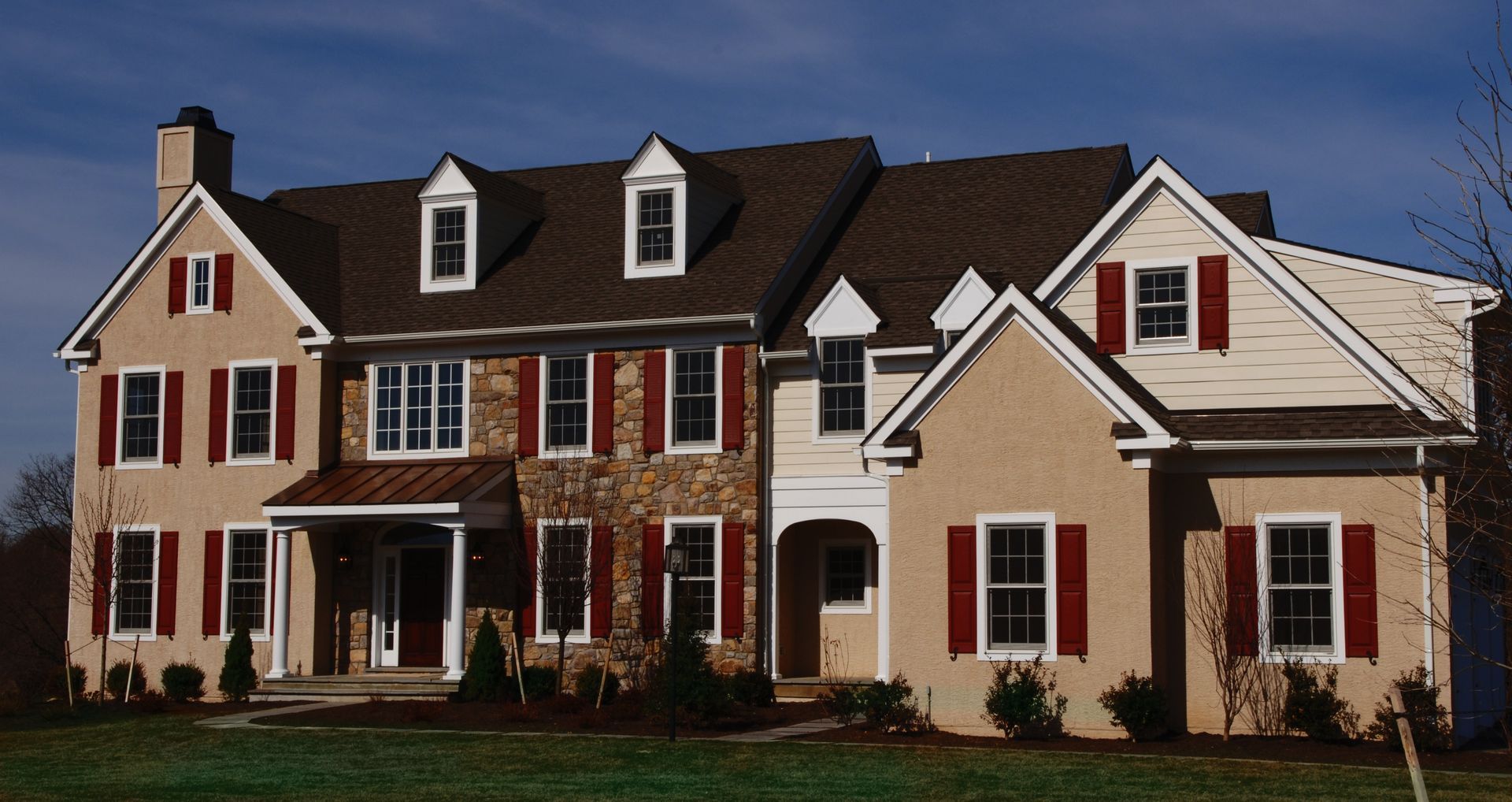 A large house with a brown roof and red shutters