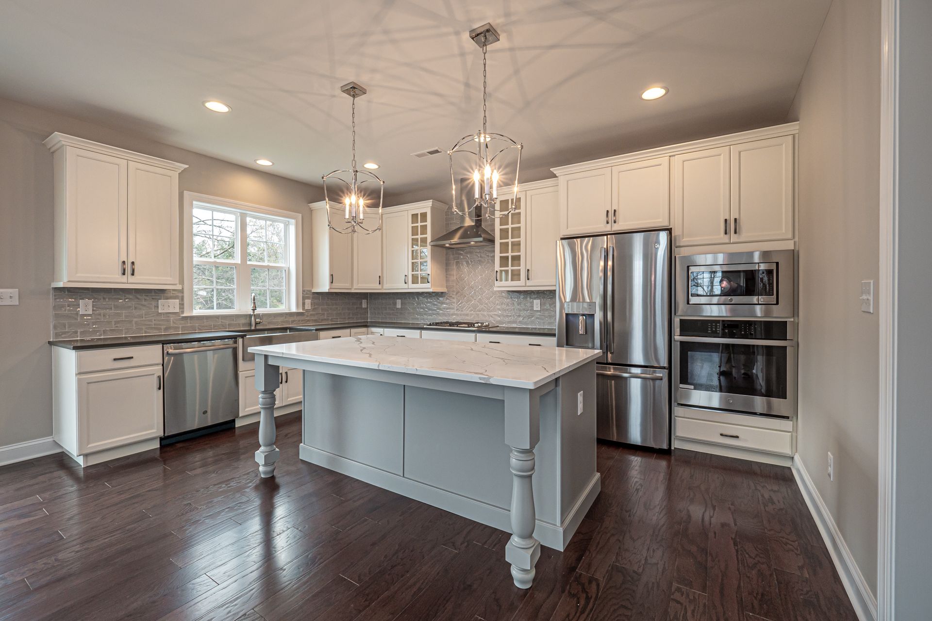 A kitchen with white cabinets , stainless steel appliances , and a large island.