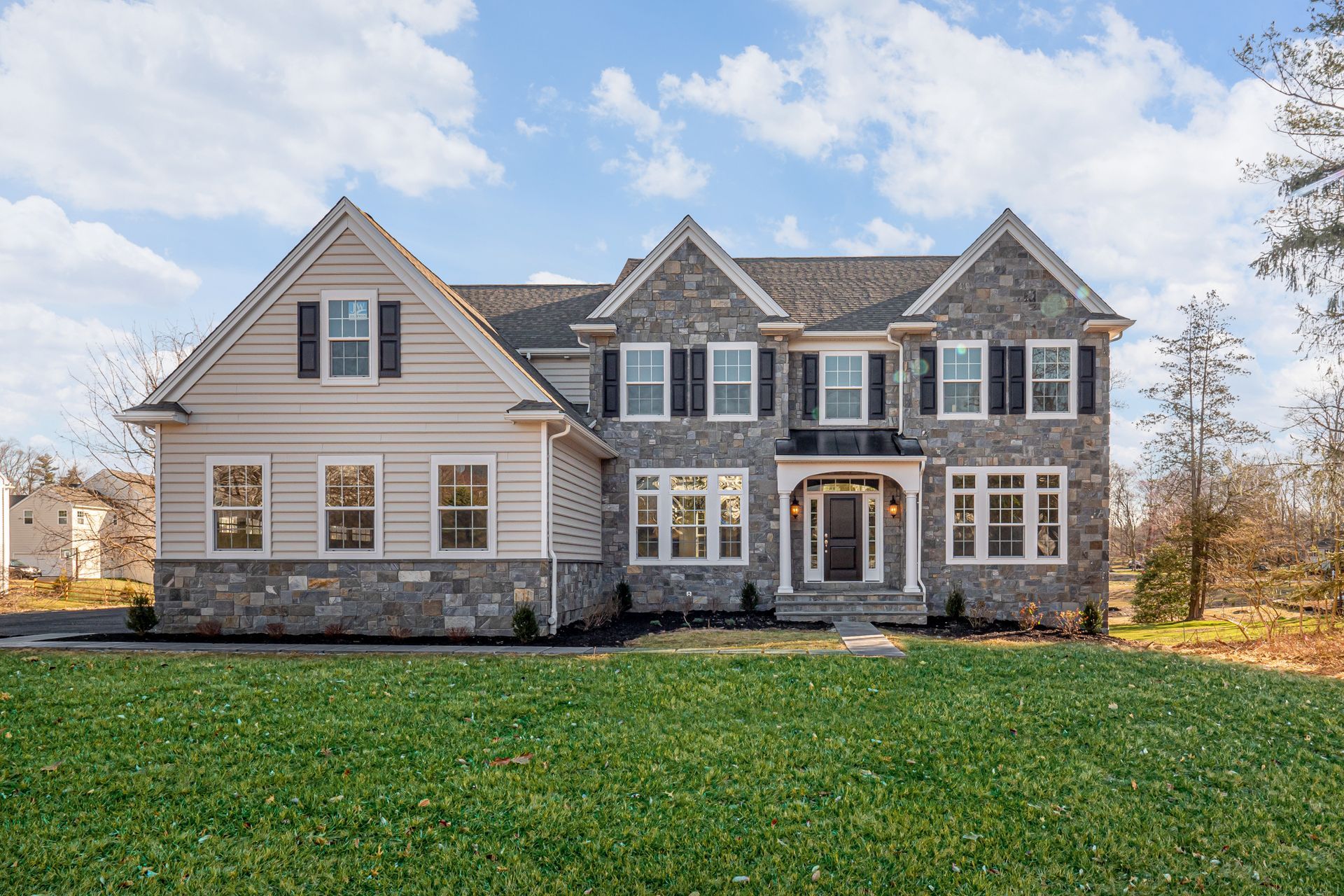 A large house with a lot of windows is sitting on top of a lush green field.