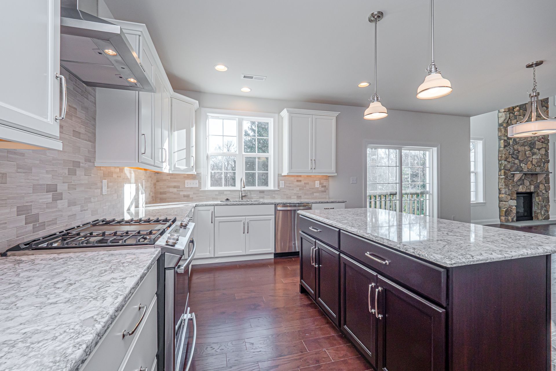 A kitchen with white cabinets , granite counter tops , stainless steel appliances and a large island.