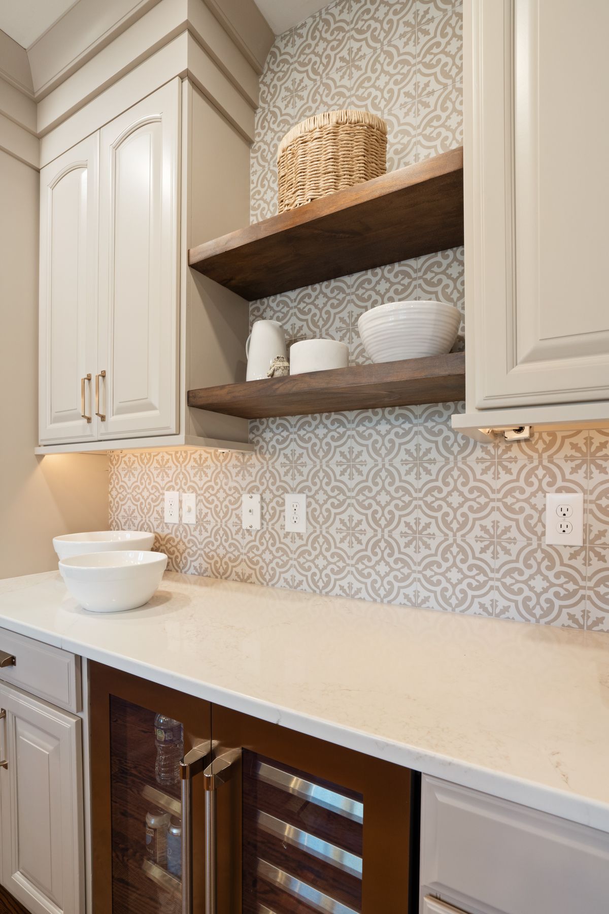 A kitchen with white cabinets , wooden shelves , and a wine cooler.