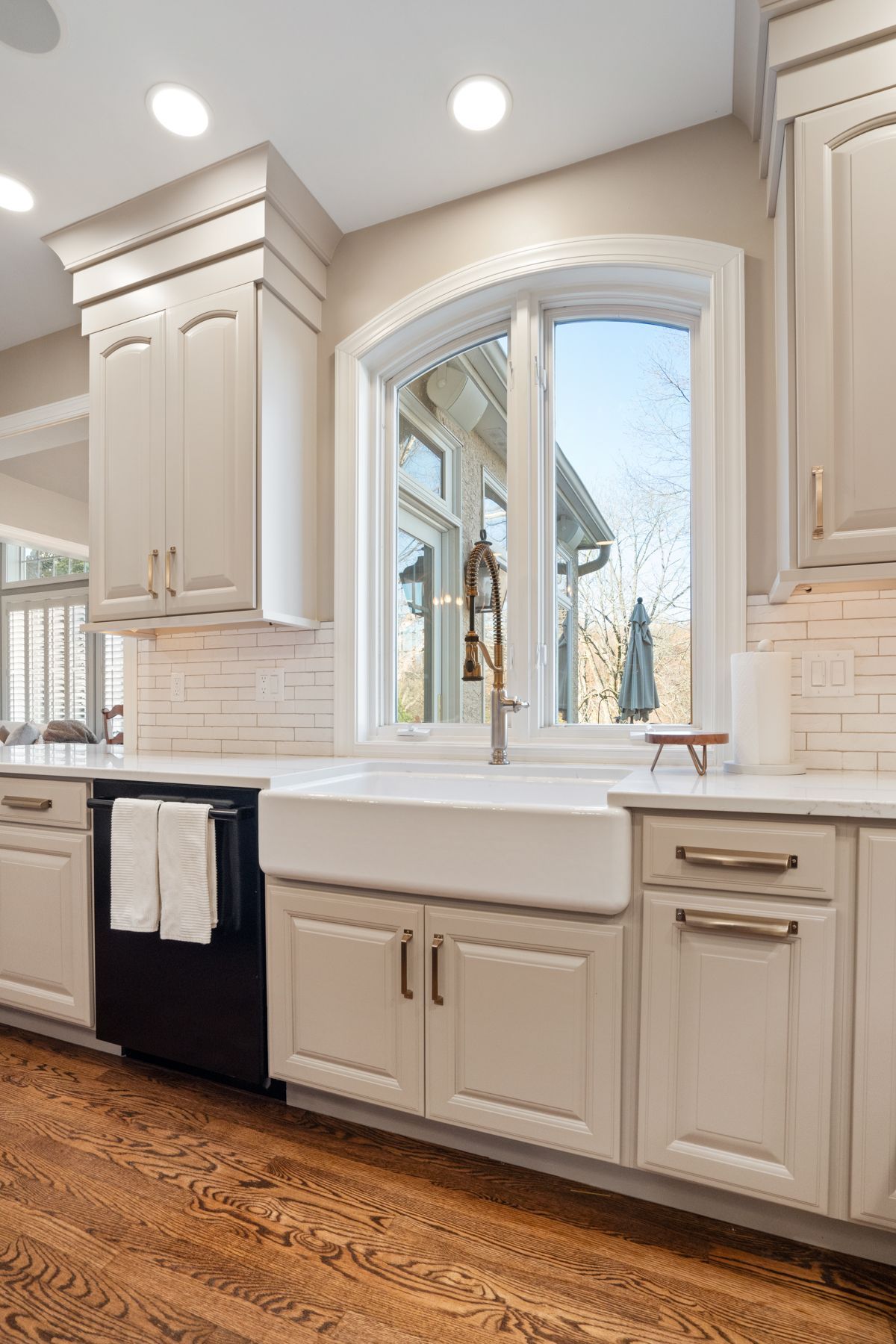 A kitchen with white cabinets , a farmhouse sink , and a window.