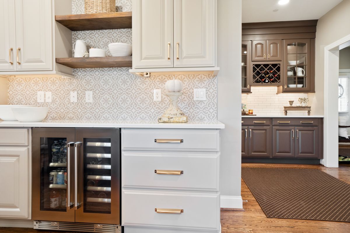 A kitchen with white cabinets and brown cabinets and a wine cooler.