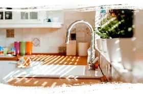 A person using a screwdriver to adjust a metallic spotlight fixture.