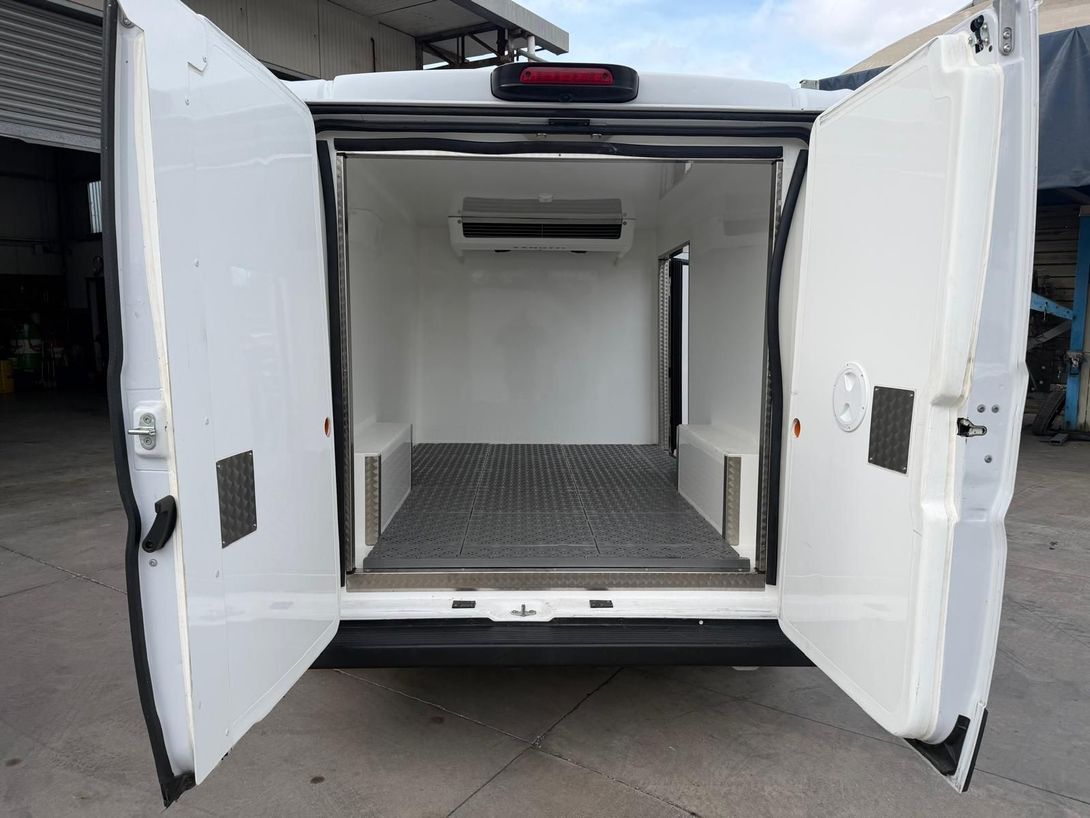 Parte posteriore del furgone aperta con interni bianchi e pianale vuoto in lamiera mandorlata.