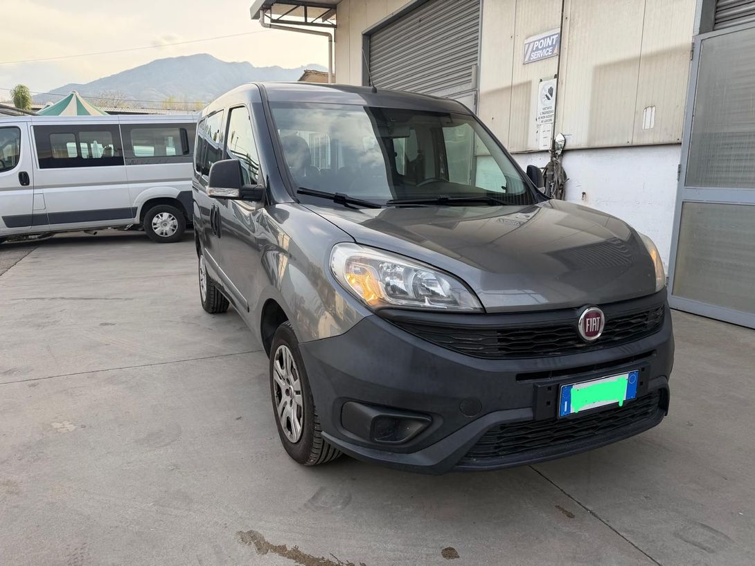 Un furgone Fiat nero parcheggiato fuori da un magazzino, con un furgone bianco sullo sfondo.