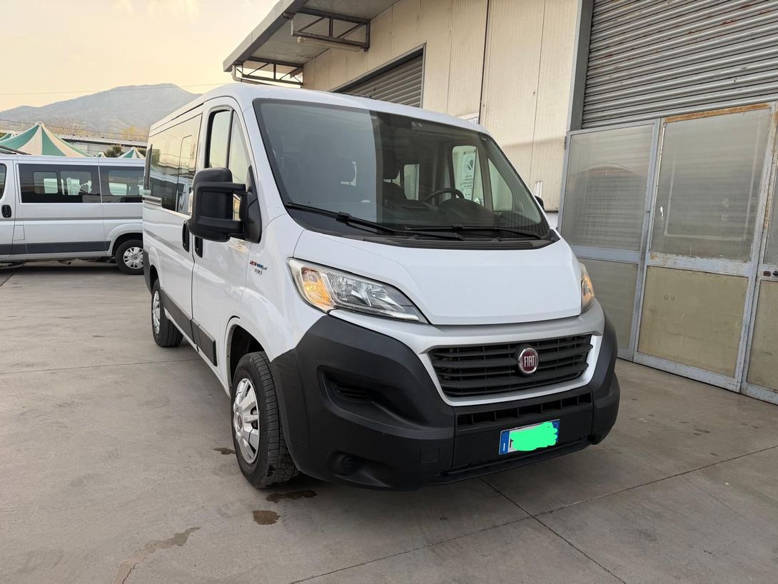 Furgone Fiat bianco parcheggiato accanto a un magazzino su un piazzale in cemento.