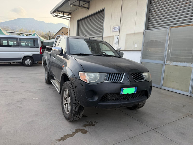 Un pick-up nero parcheggiato fuori da un edificio industriale, con le montagne sullo sfondo.
