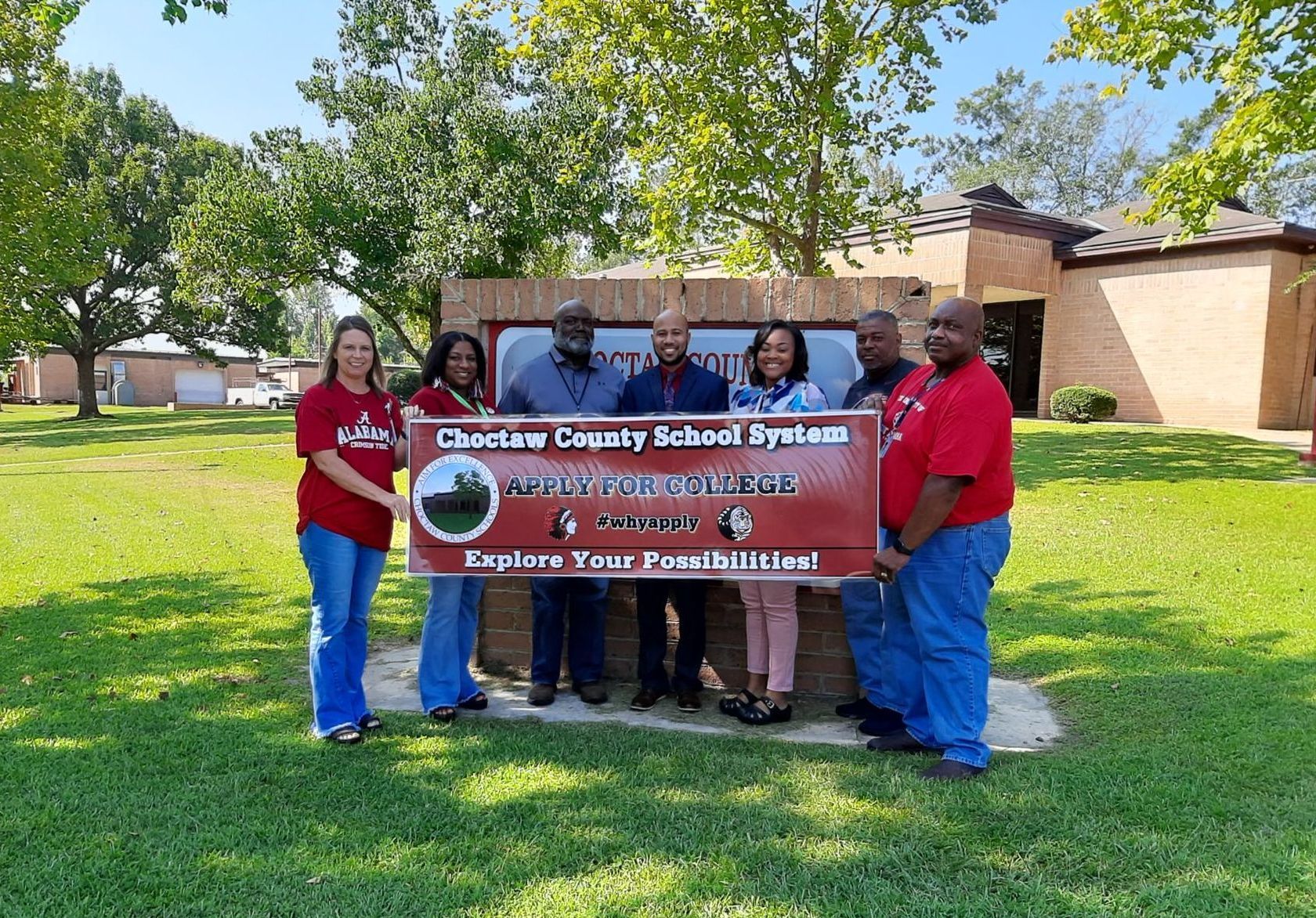 a group of people standing in front of a sign that says cheetah county school system