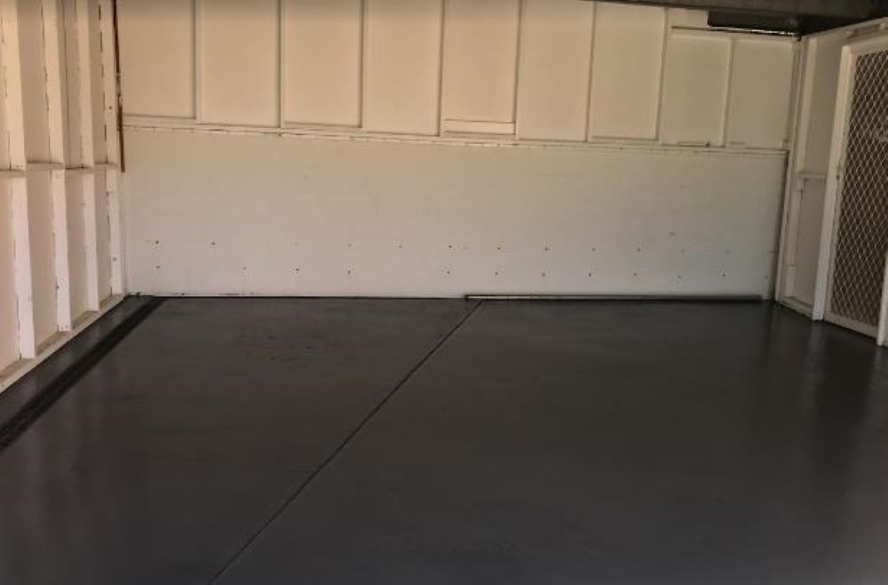 An Empty Garage With a Black Floor and White Walls — A&J Painting In Gungahlin, NT
