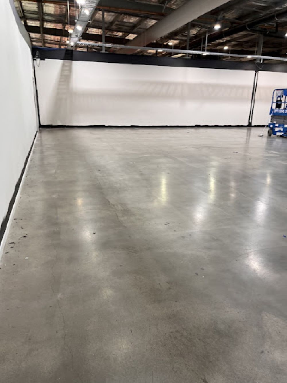 A Large Empty Warehouse With a Concrete Floor and a White Wall — A&J Painting In Gungahlin, NT