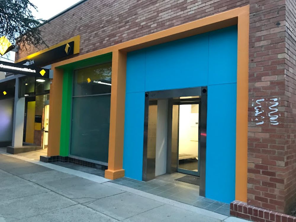 A Brick Building With a Blue Green and Orange Facade — A&J Painting In Tuggeranong, NT
