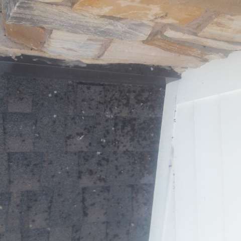 Dark, textured surface with dark spots beneath stone and white wall.