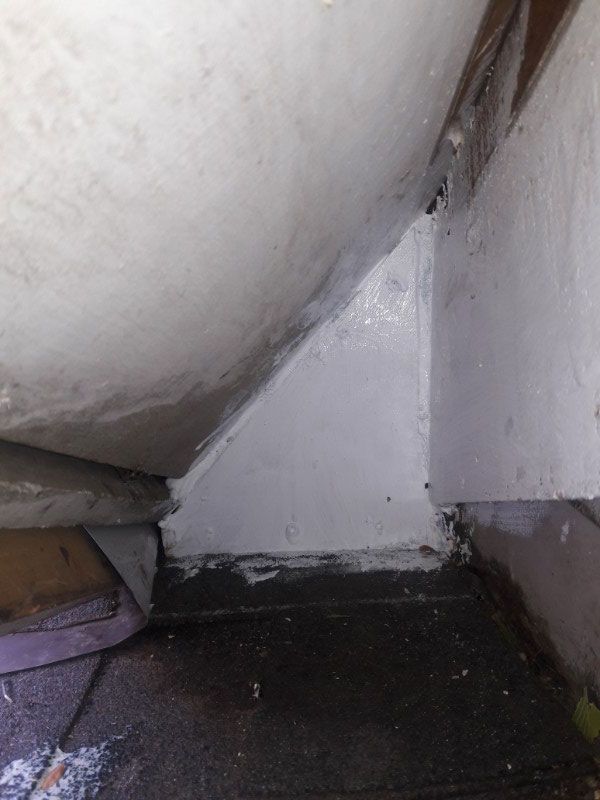 White painted support structure under a white surface, dark flooring below, small triangular area visible.