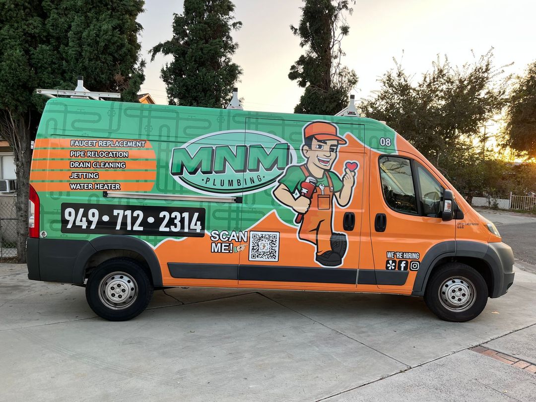 a mnm plumbing van is parked in a driveway .