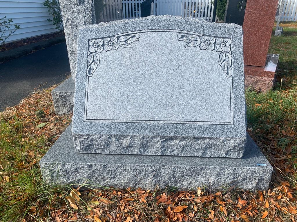 A gravestone is sitting in the grass next to a road.