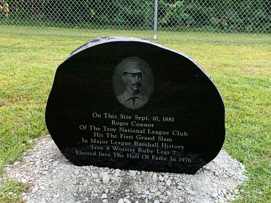 A black stone with a picture of a man on it is in the grass.