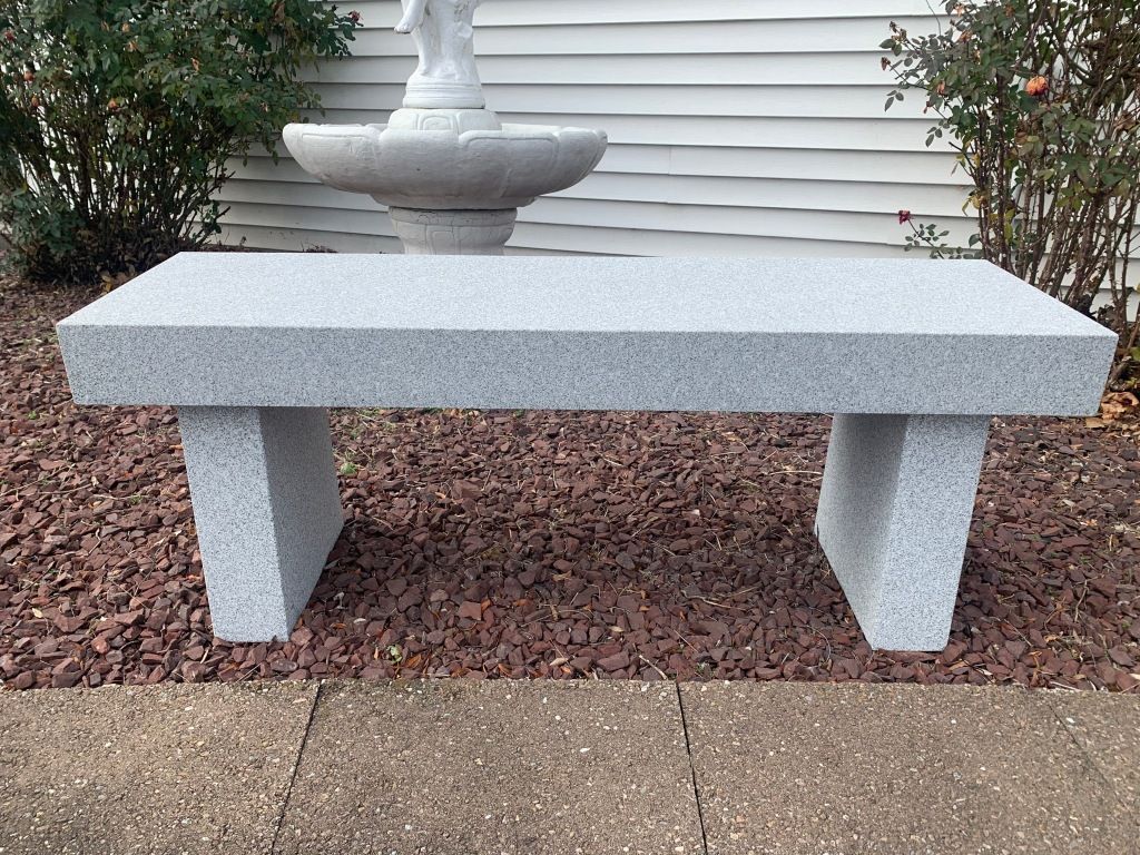 A stone bench is sitting in front of a fountain