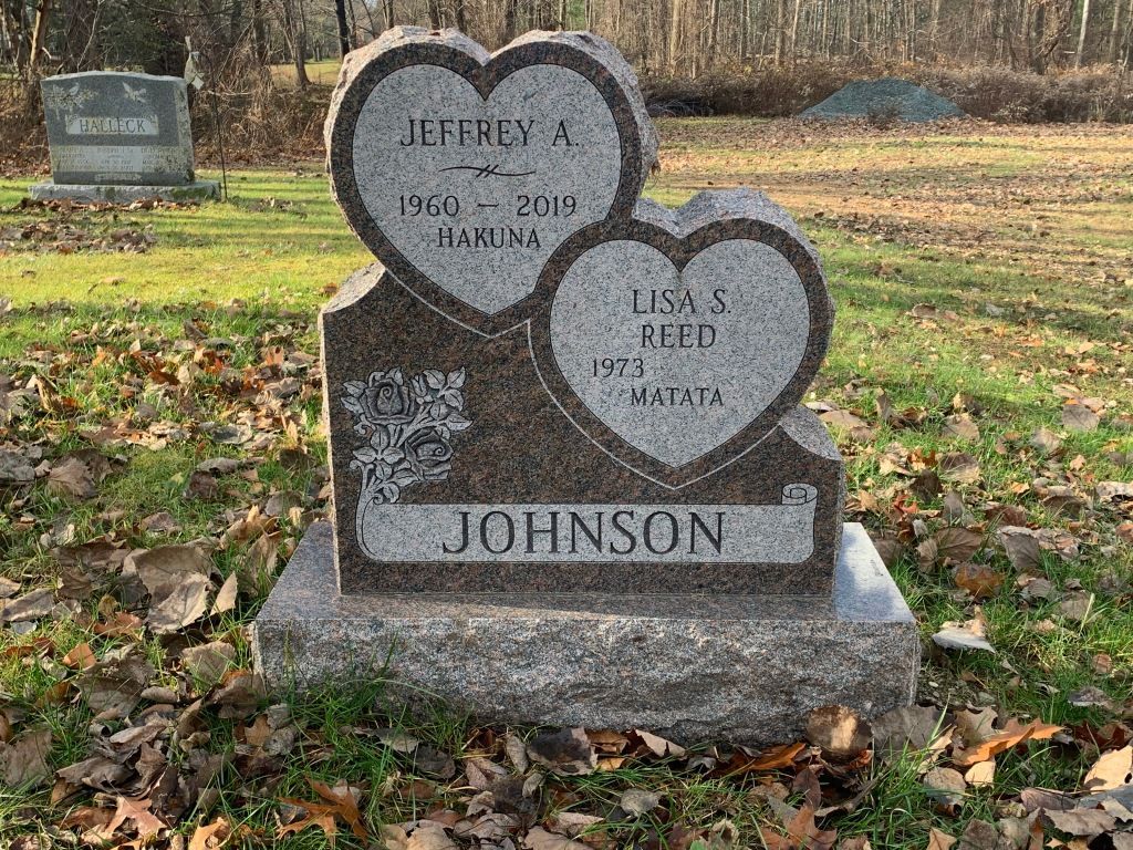 A gravestone with two hearts on it is in a cemetery.