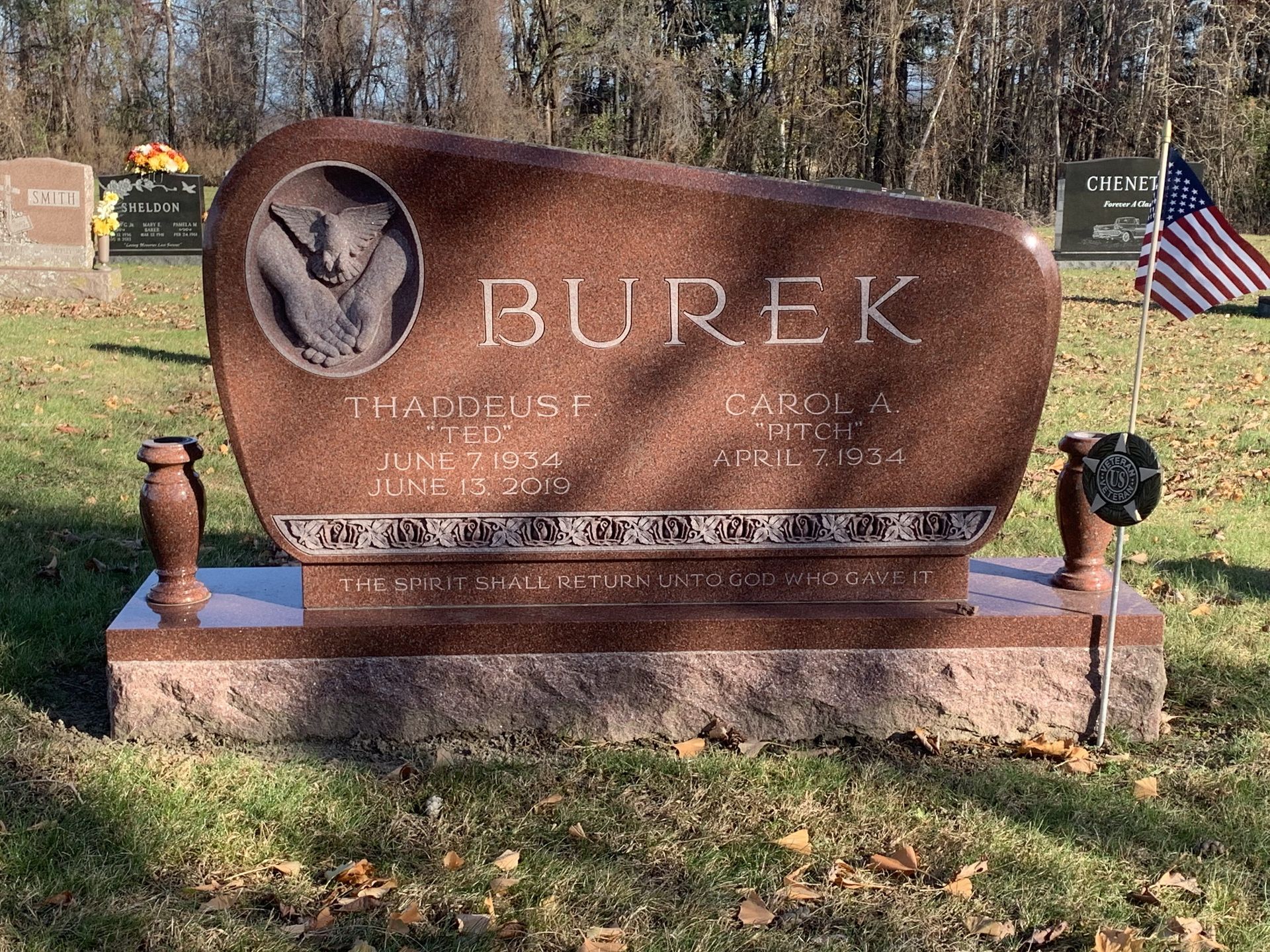 A gravestone in a cemetery with a bear on it.