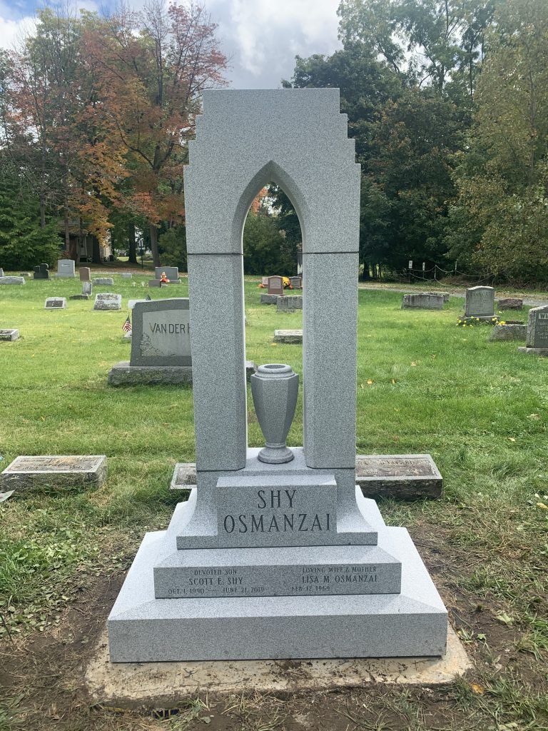 A gravestone with a trophy in the middle of a cemetery.