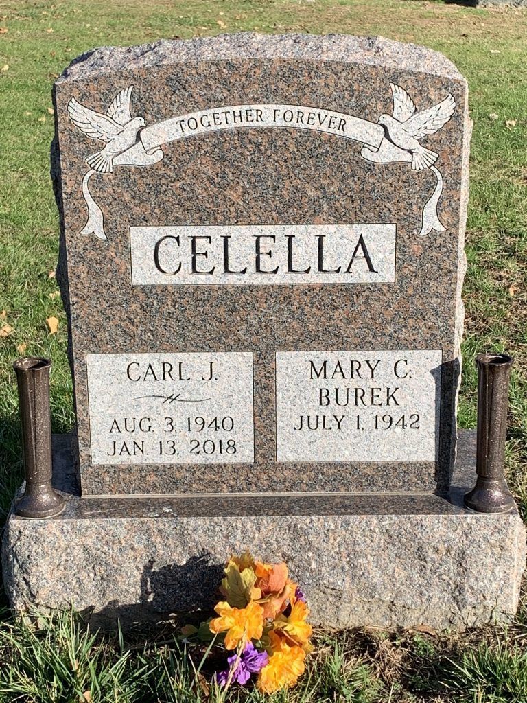 A gravestone in a cemetery with flowers in front of it.