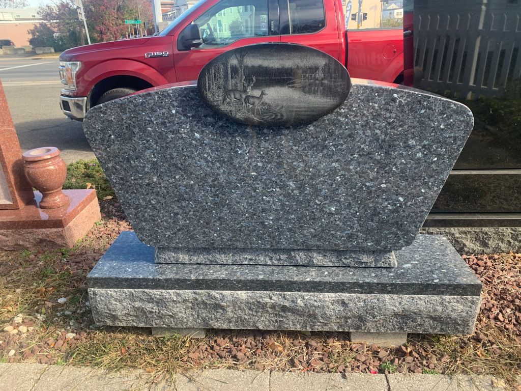 A gravestone is sitting on the side of the road next to a red truck.