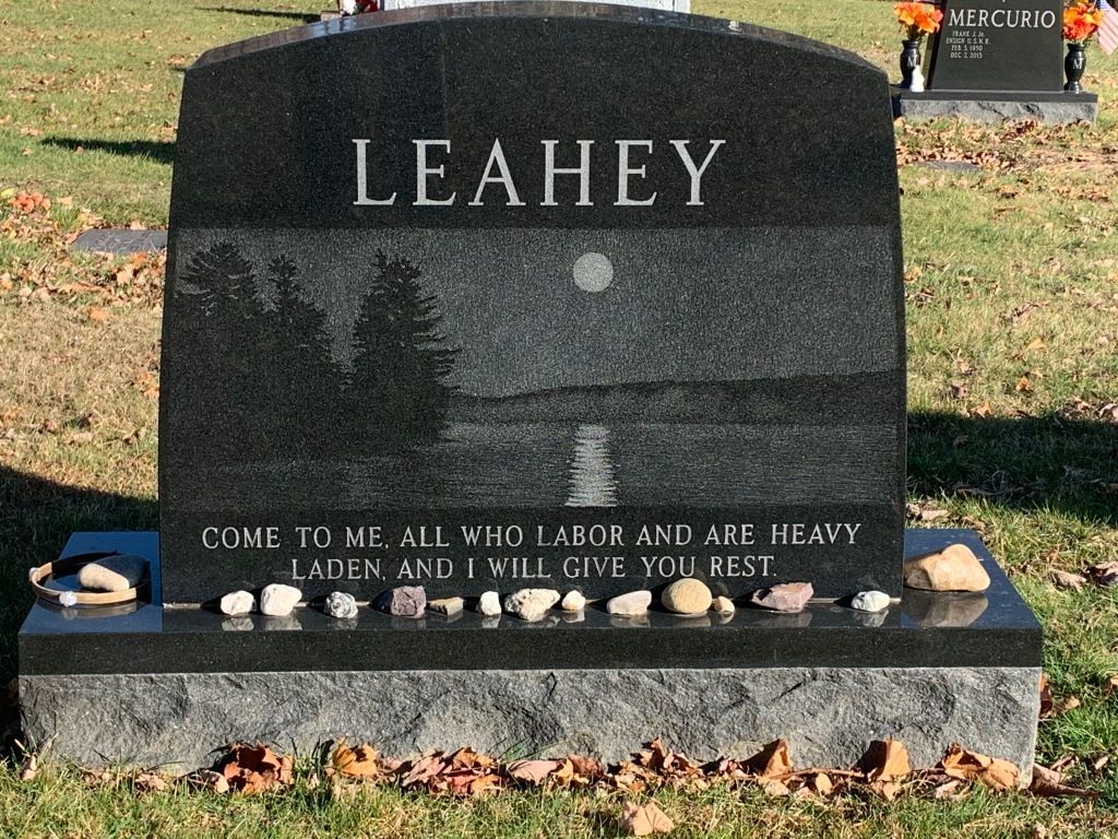 A gravestone for leahey is in a cemetery.