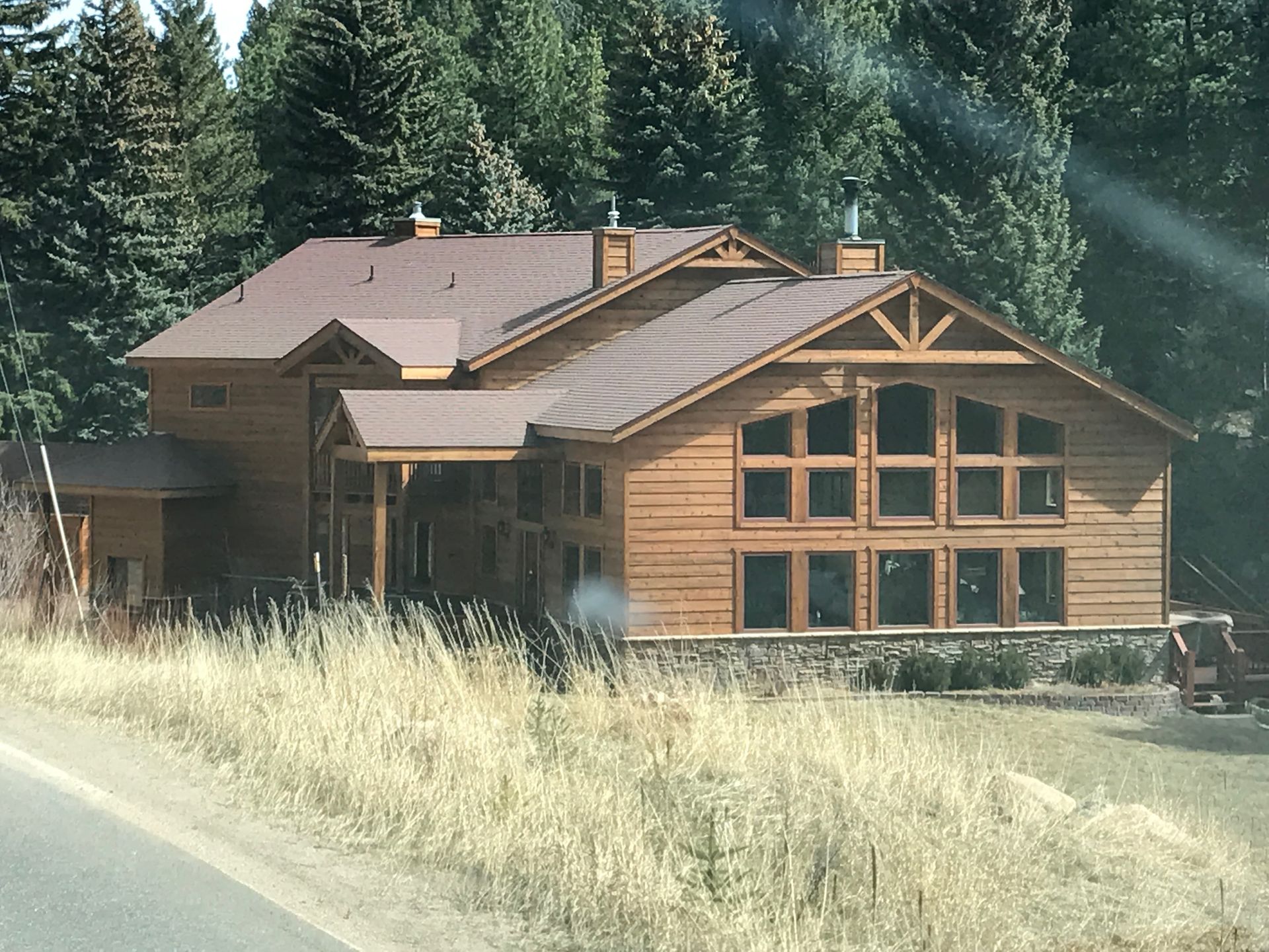 A large wooden house sits on the side of a road