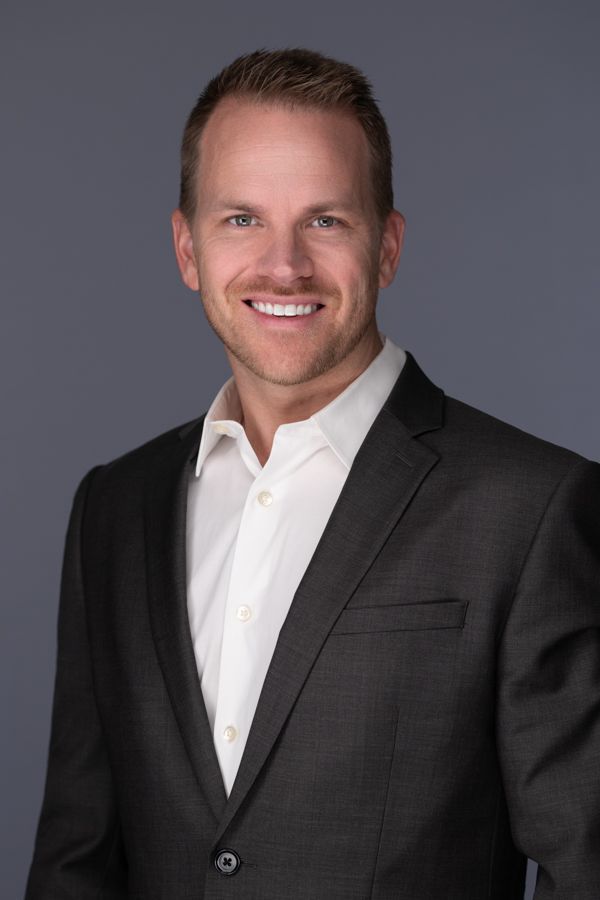 A man in a suit and white shirt is smiling for the camera.