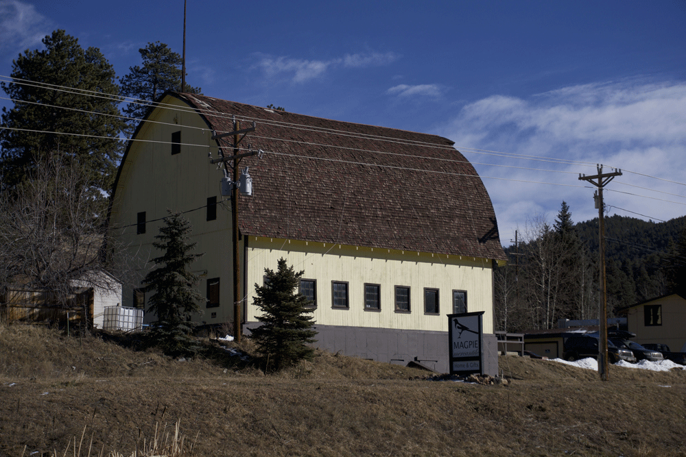 A yellow building with a red roof is in the middle of a field