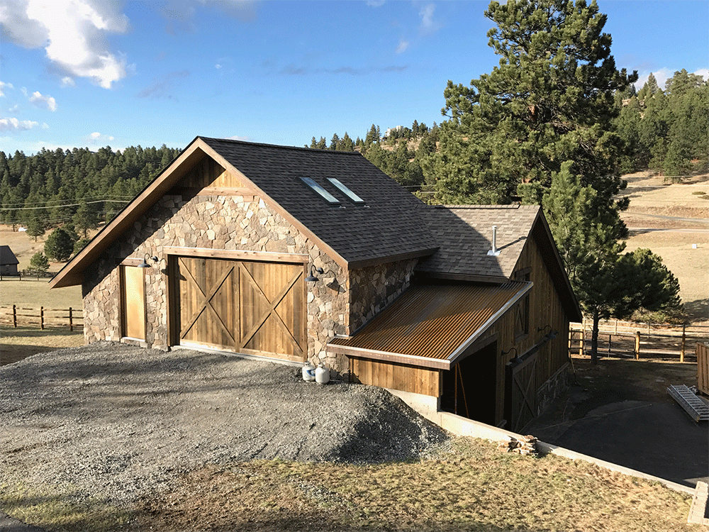 A large stone building with a wooden garage door is sitting on top of a dirt hill.