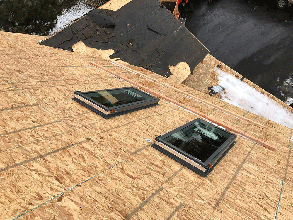 Two skylights are sitting on top of a wooden roof.