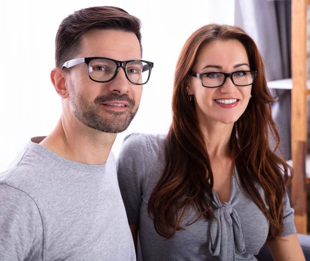 A man and a woman wearing glasses are posing for a picture.