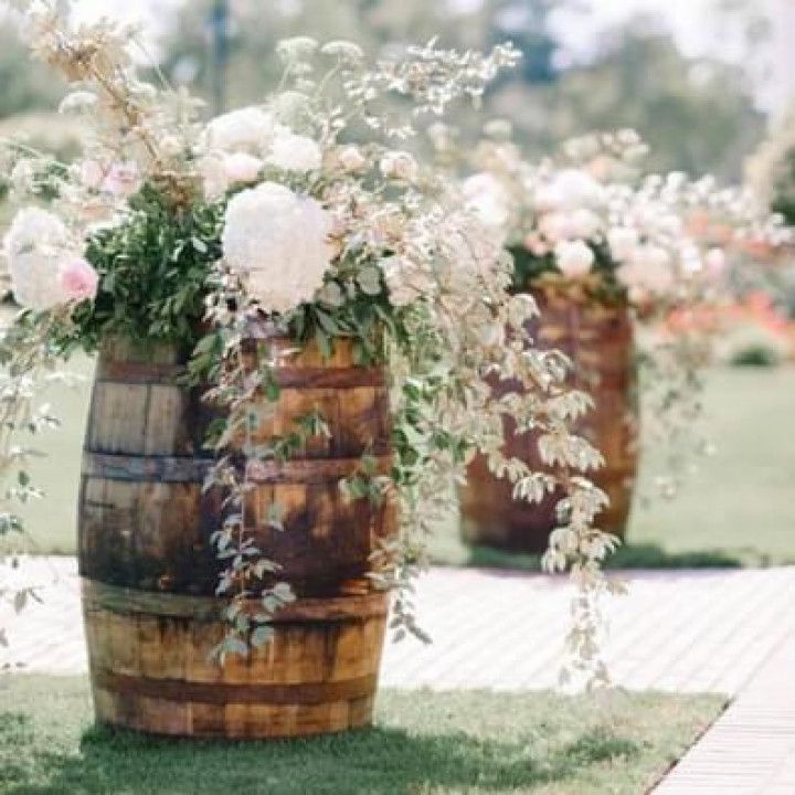 Two wooden barrels filled with flowers are sitting on the grass.