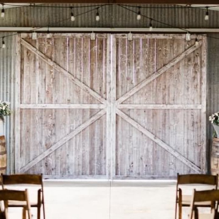 A large wooden barn door with chairs in front of it.