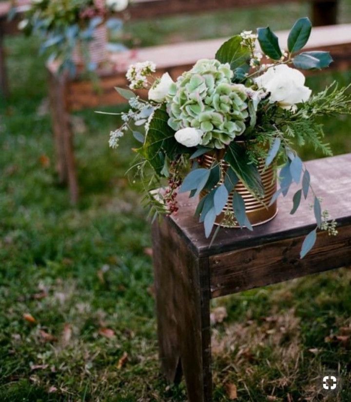 A vase of flowers is sitting on a wooden bench.