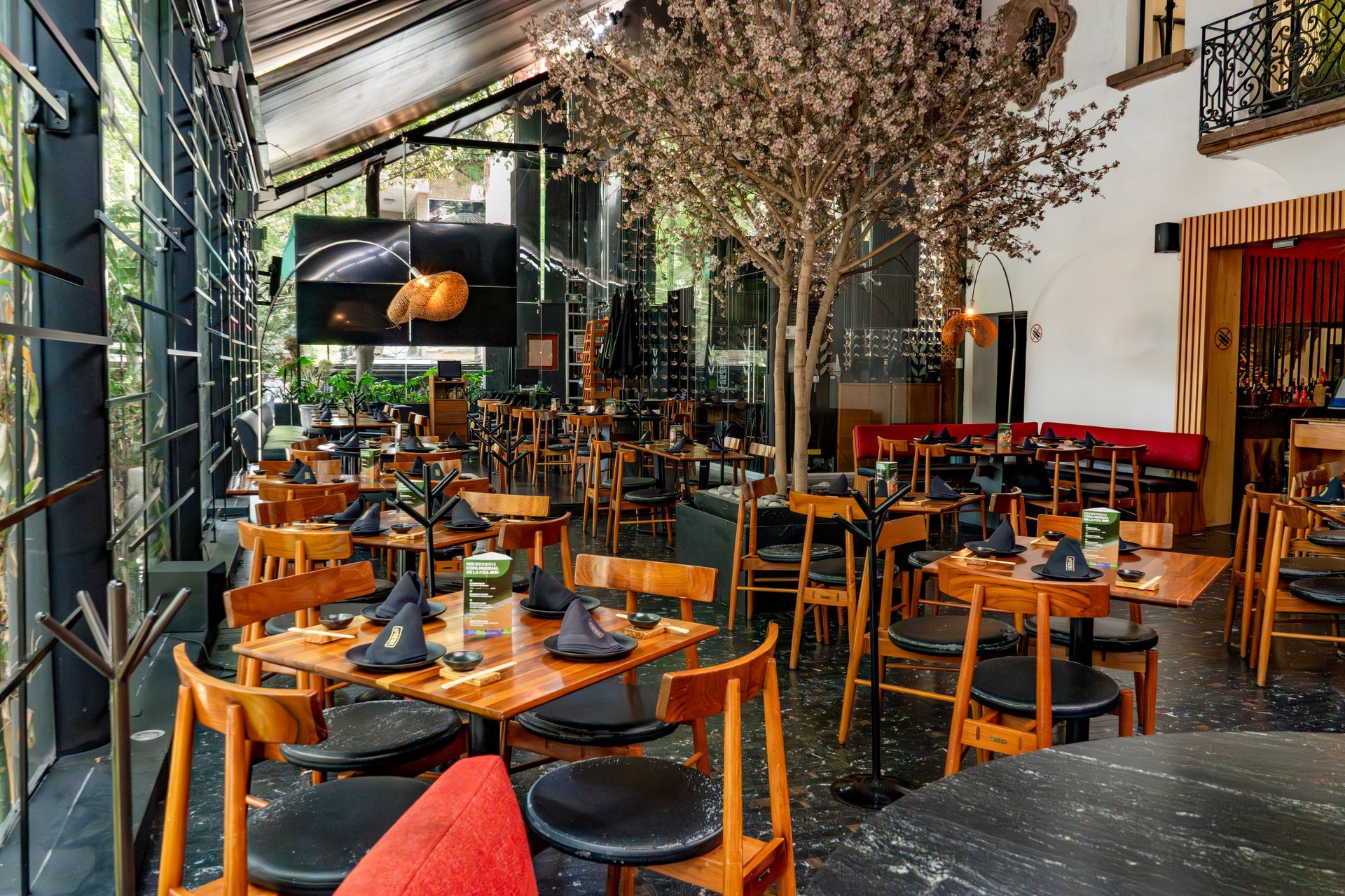 Patio con madera, sillas negras y cojines naranjas.