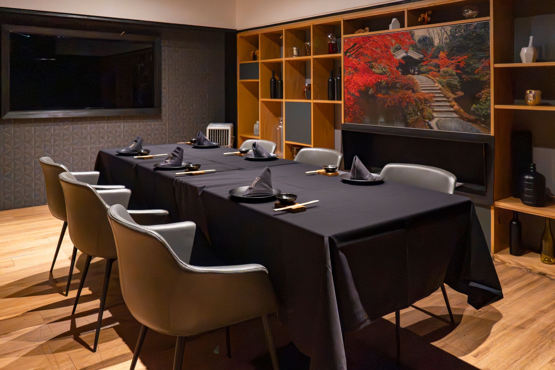 Comedor moderno con una mesa larga negra, sillas beige y un cuadro de un paisaje rojo en la pared.