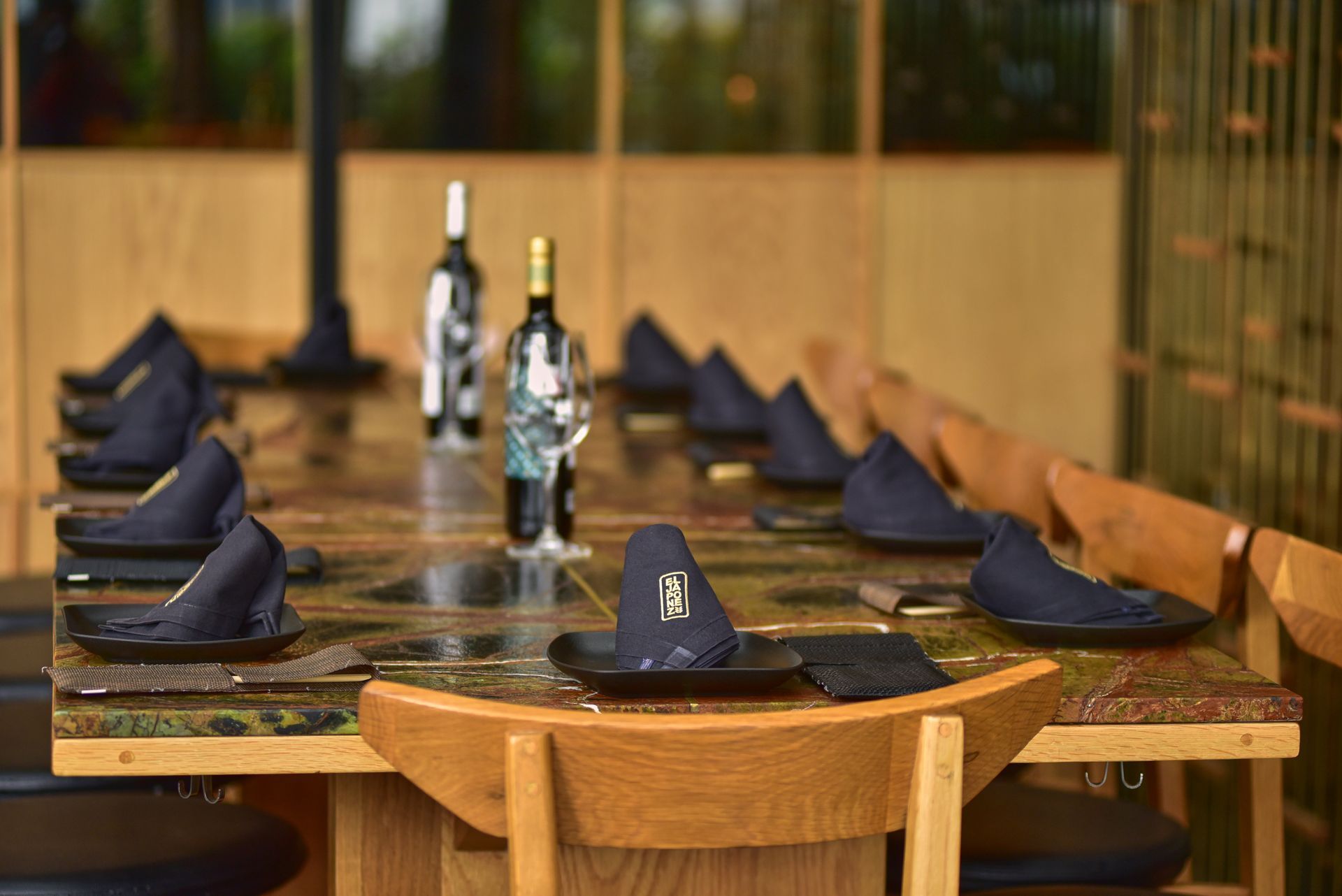 Mesa puesta para una comida formal con servilletas azules, vasos y botellas en un comedor de restaurante.