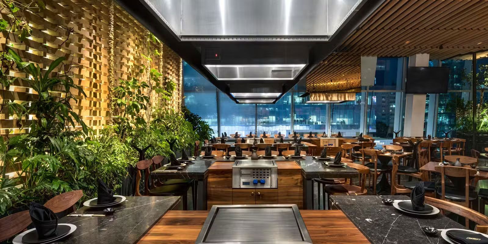 Restaurante moderno con muro verde y vista urbana.