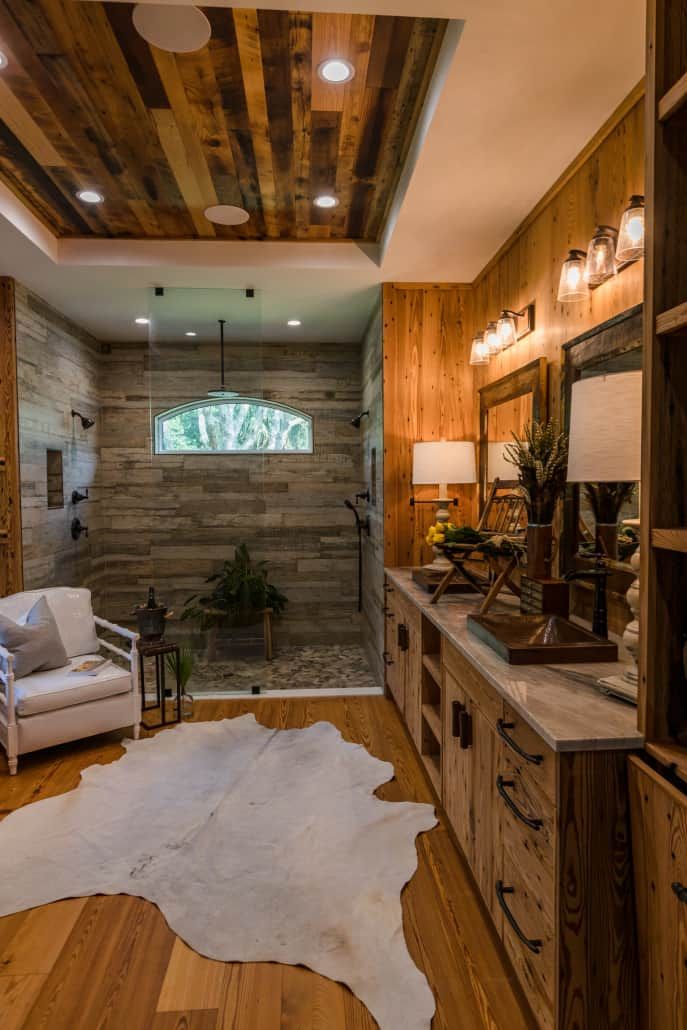 Rustic bathroom with wood paneling, stone shower, and cowhide rug.