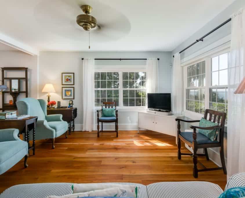 Living room with hardwood floors, blue armchairs, and a TV near a window.