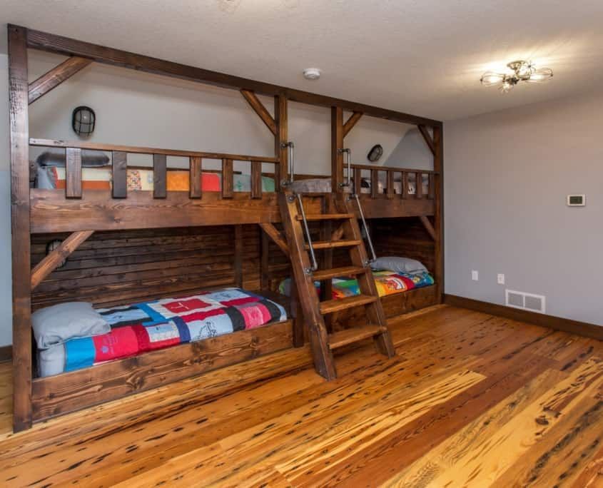 Rustic bunk beds with wooden frame in a room with hardwood floors and gray walls.